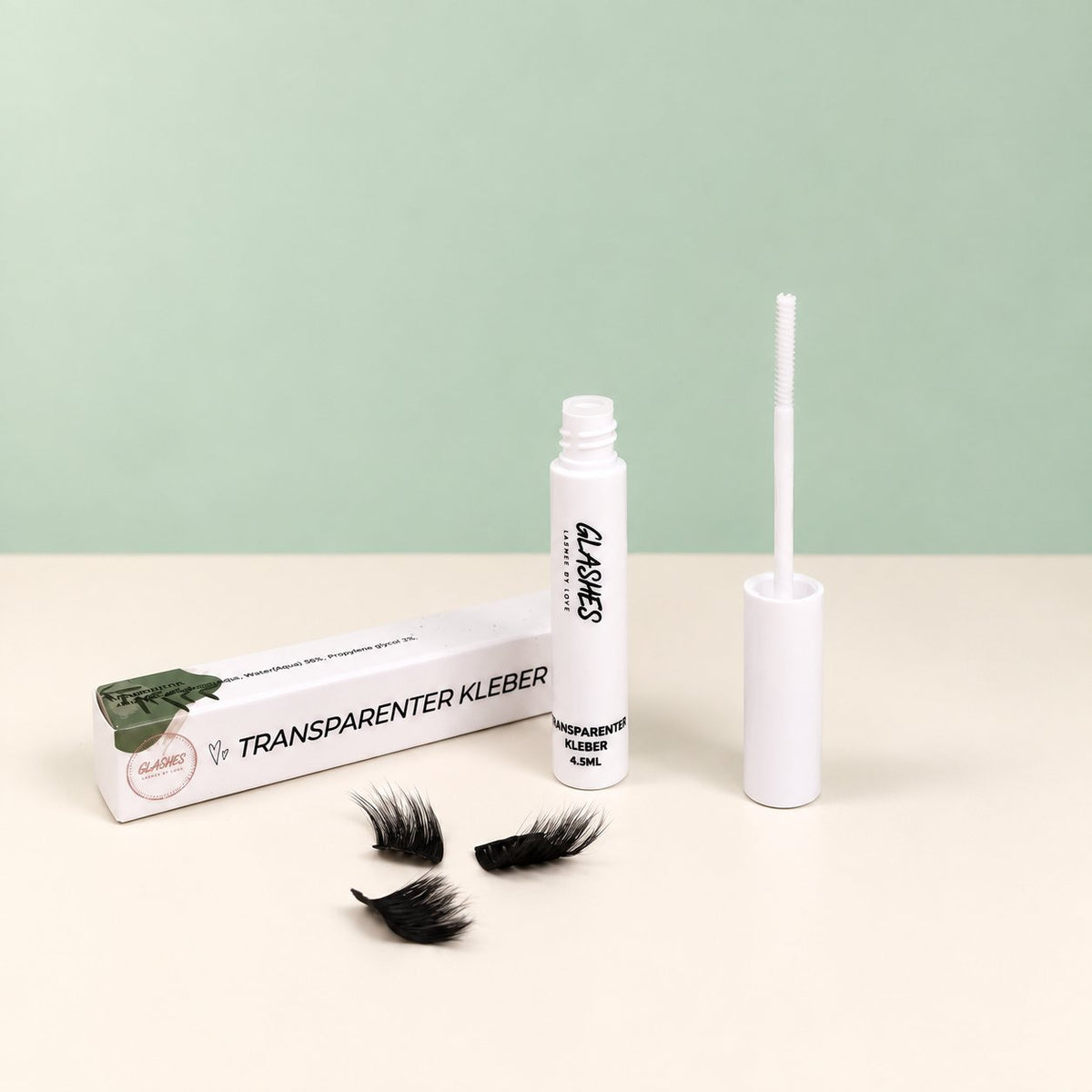Glashes transparenter Wimpernkleber mit geöffnetem Applikator und Verpackung